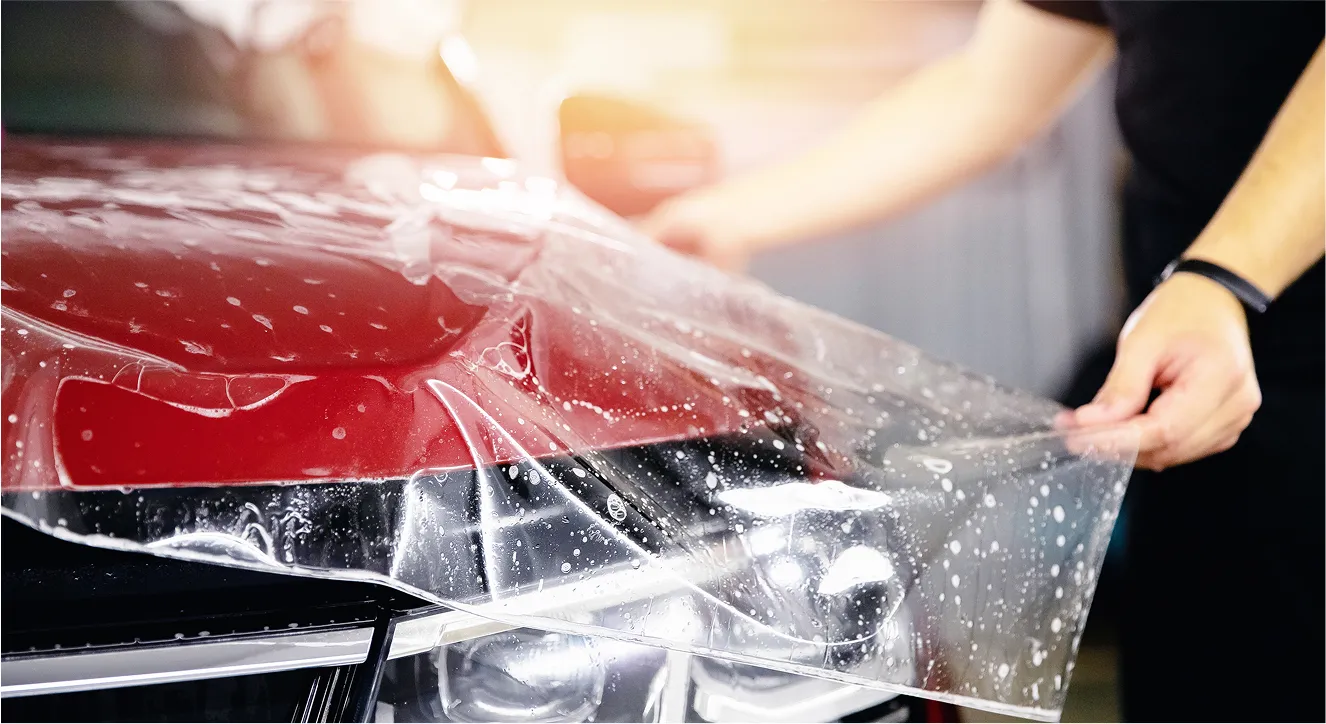 man installing ppf onto a red vehicle